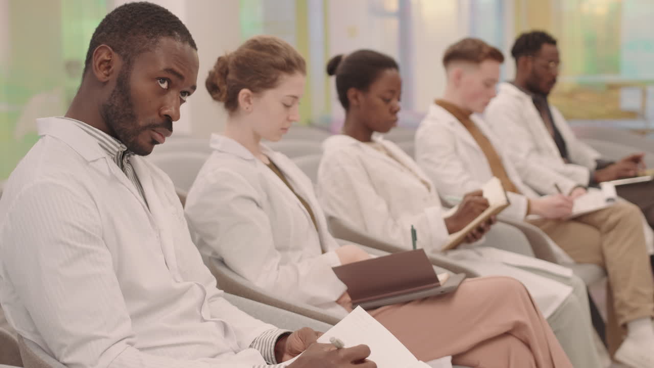 Diverse Medical Students in Row Taking Notes at Lecture