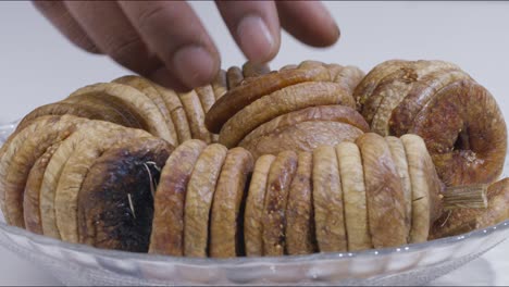 Close-up-static-shot-of-hand-picking-up-dried-fig-from-plate-on-table