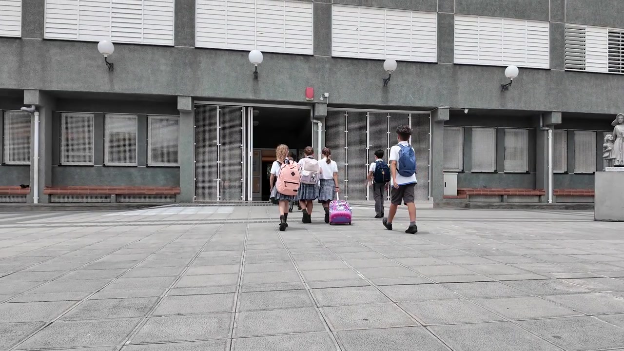 Grupo de escolares entrando juntos a la escuela.