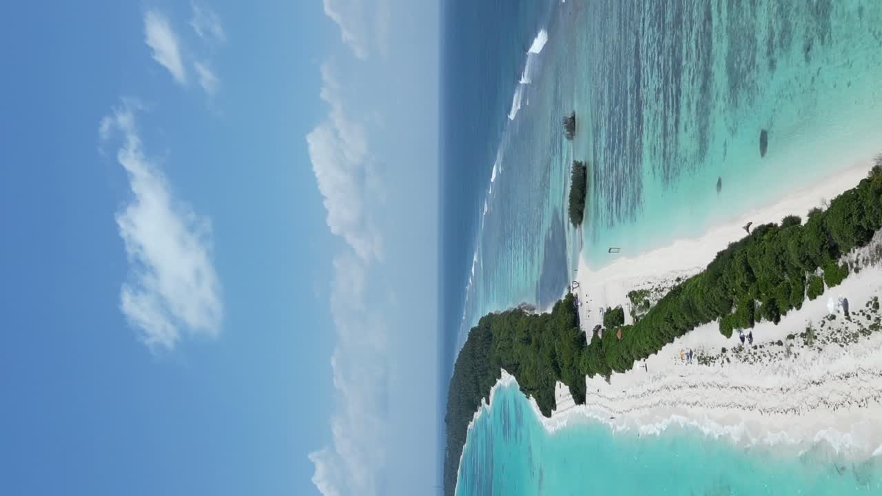 Vertikaalinen ilmakuva Dhigurah-saaresta pitkän valkoisen hiekkasärkän ja turkoosin kirkkaan veden yllä, Malediivit.