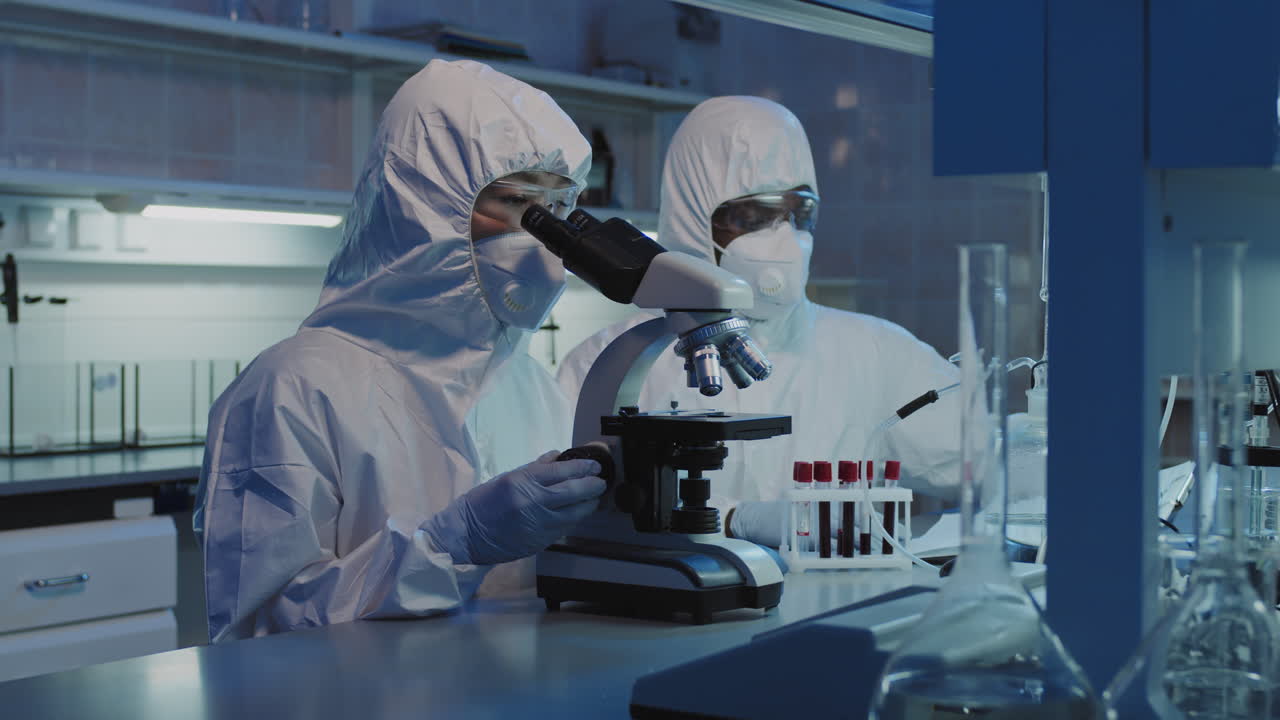 Scientists in Coveralls and Face Masks Doing Research in Lab