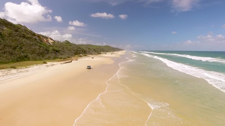 A car drives along the beach on Fraser Island off the coast of Queensland Australia