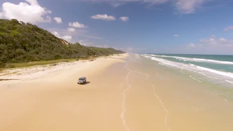 un automóvil conduce a lo largo de la playa en la isla de fraser frente a la costa de queensland, australia