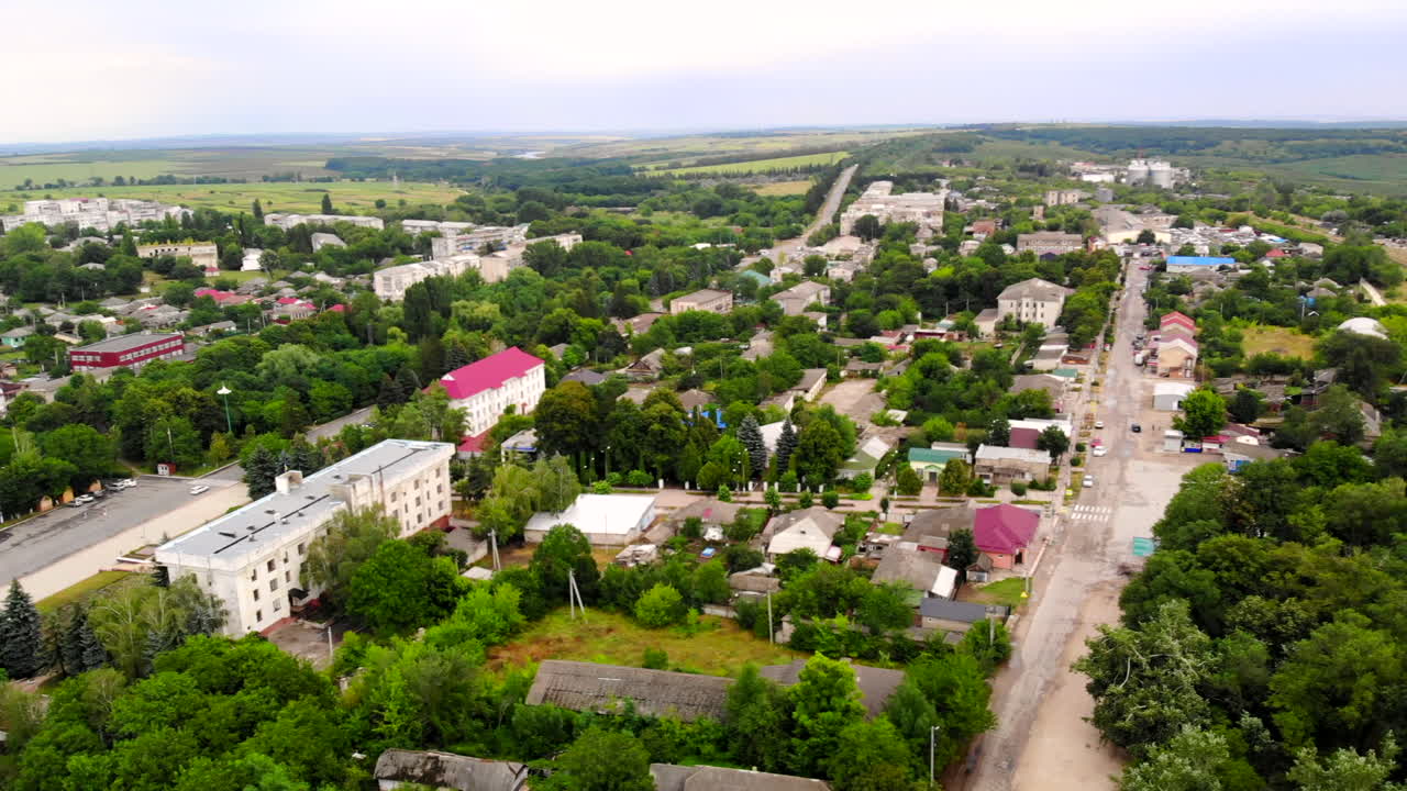 Aerial drone shot of Donduseni city with multiple residential buildings and greenery and fields in Moldova