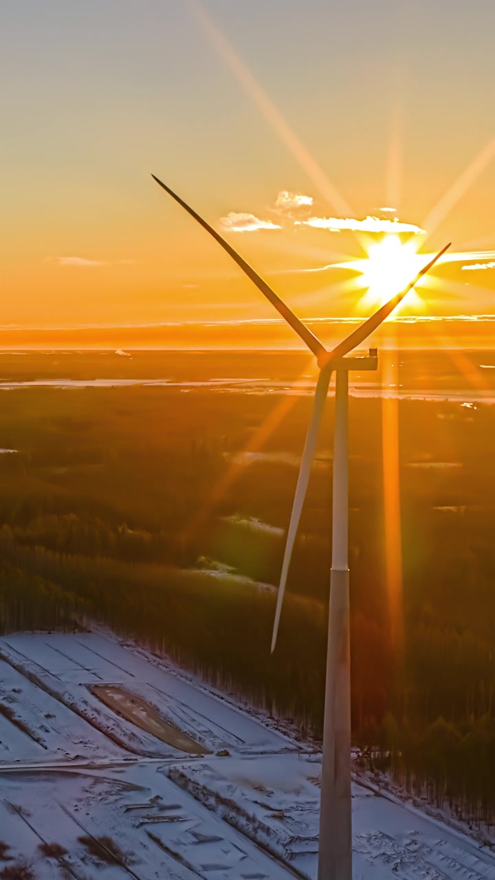 Pale di turbine eoliche ruotano all'alba su un paesaggio rurale innevato, uno scenario di energia rinnovabile