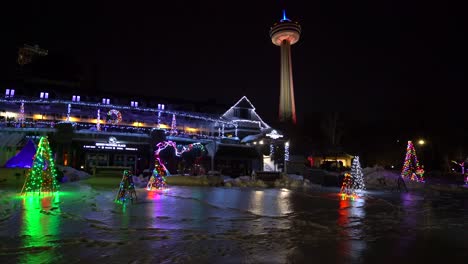 niagara falls queen victoria place with skylon tower in distance night with frozen ice and snow during winter festival of lights christmas trees reflecting on ice during winter close-up