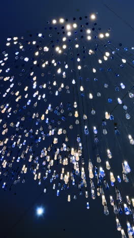 numerous white and blue lamps hanging from the blue ceiling. low angle view at the decorative illumination of the room. vertical video.