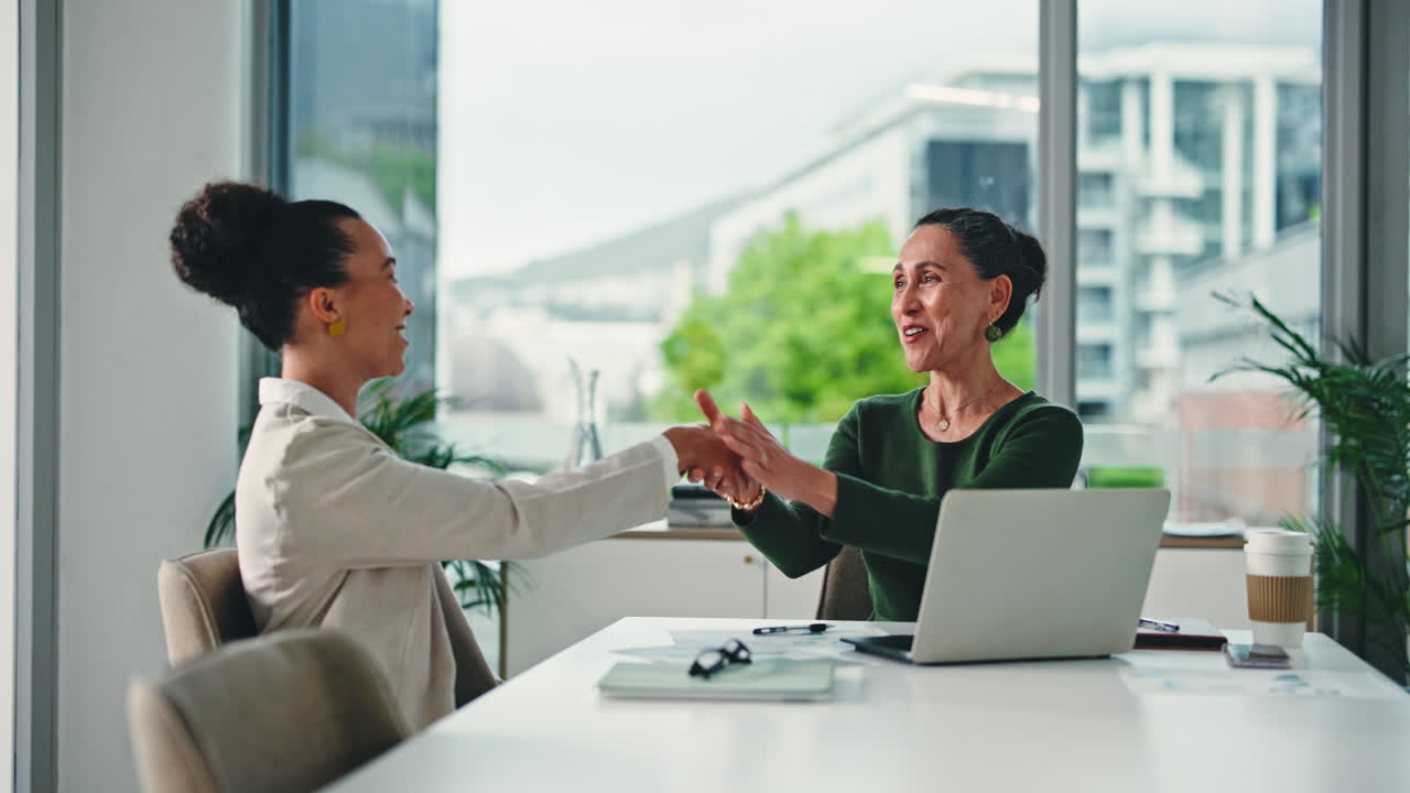 Two businesswomen celebrating a successful collaboration in a modern office