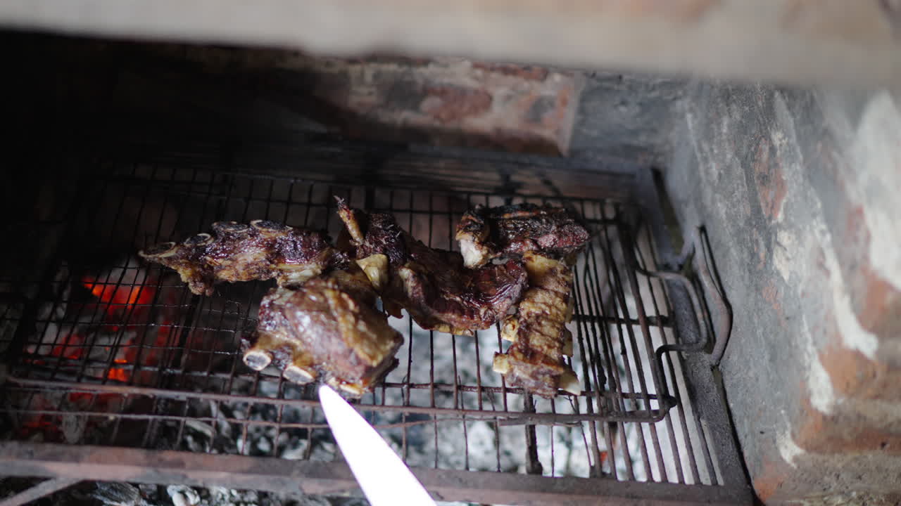 Argentinian grilled meat cuts cooking over hot coals in a rustic brick grill