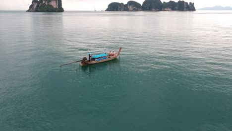 imágenes de drones de un bote de cola larga navegando alrededor de las islas de tailandia con las formaciones rocosas de piedra caliza que sobresalen del agua y el océano en el fondo-9