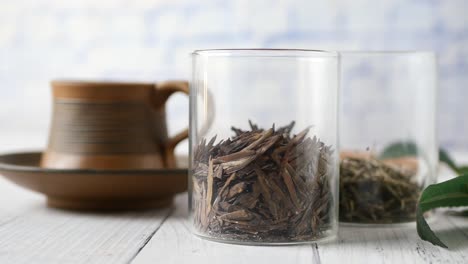 dried tea leaves in glass jars and tea cup