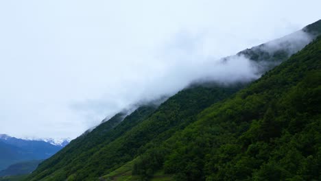 wide cinematic shot of rolling clouds crossing a dark green mountain crest in the italian alps. shot at villa di tirano, sondrio, italy (italia)