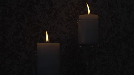 two lit candles in glass holders