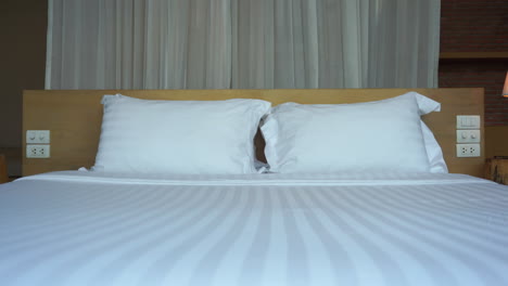 Cama-De-Hotel-Con-Colcha-Y-Almohadas-De-Rayas-Blancas-Y-Cortinas-Que-Soplan-El-Viento