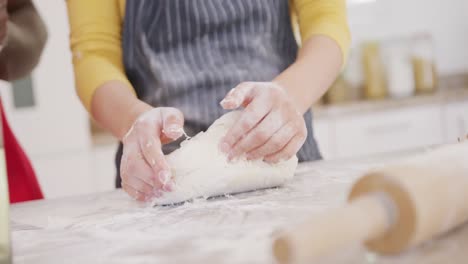 Close-up-of-couple-wearing-aprons-and-baking-in-kitchen