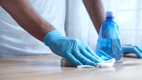 limpiando una mesa con guantes y una botella de spray