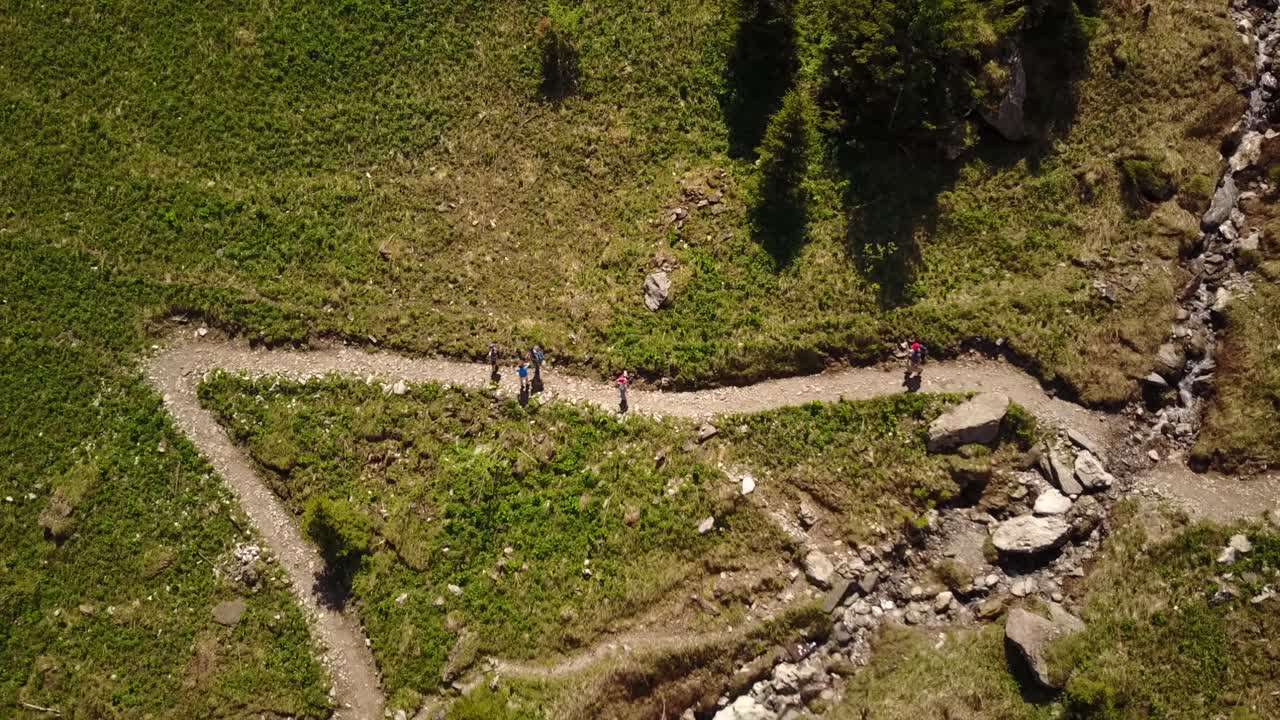 senderismo familiar en los alpes suizos junto a un río, vista superior por drones