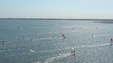 Drone---Aerial-shot-of-many-surfers-on-a-blue,-wavy-and-windy-sea-on-a-sunny-day-with-white-clouds-on-a-island,-Zeeland,-Netherlands,-25p