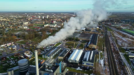 steaming factory near small township in early winter, aerial view