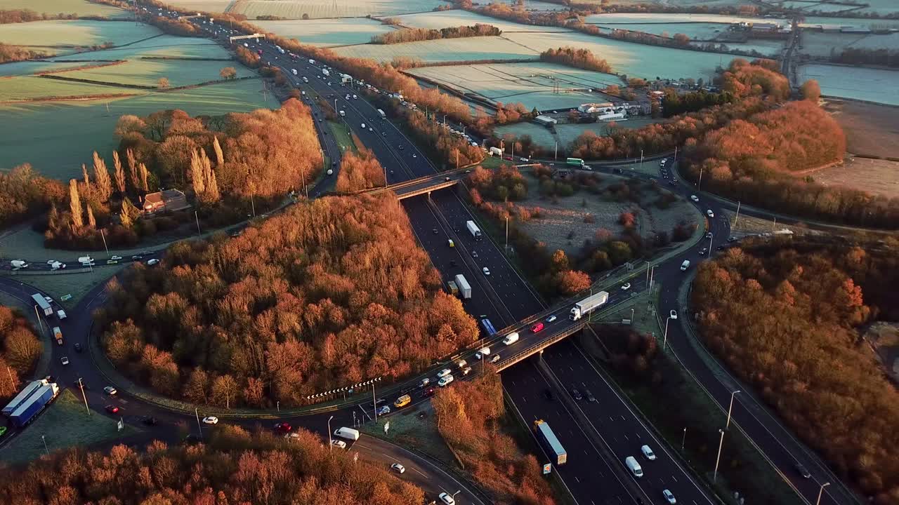 Drone Aerial View Of A Busy Motorway Junction Sliding Left To Right With Cars And Trucks In The Winter With Orange And Brown Trees
