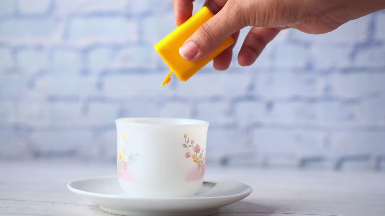 손으로 감미료를 컵에 부어 넣는 것