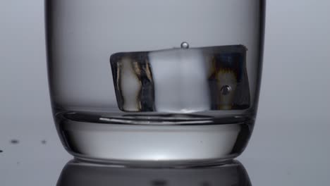cubos de hielo cayendo en un vaso de agua