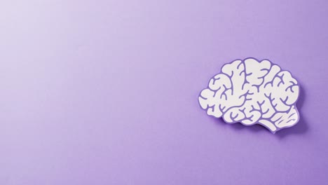 video of purple and white paper brain on purple background with copy space