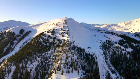 Neigen-Sie-Die-Drohne-Nach-Oben,-Um-Einen-Waldbedeckten-Berg-Zu-Sehen,-Der-Mit-Schnee-Bedeckt-Ist