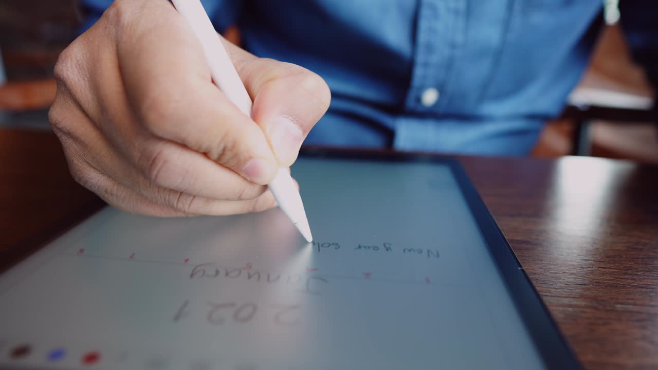 A young businessman wearing a surgical mask is doing a video conference with customers via a tablet that is connected to the Internet