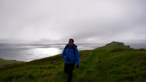 Hombre-Caminando-Hacia-La-Cámara-En-Invierno-Chaqueta-Azul-Senderismo-Mykines,-Islas-Feroe