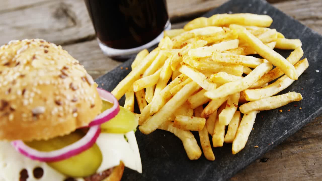 hamburguesa, papas fritas y bebida fría en tablero de pizarra