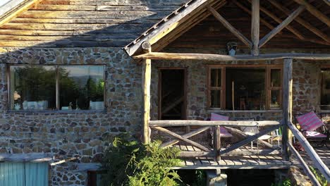 front of dreamy wood and stone house in mountains at sunset in slow motion