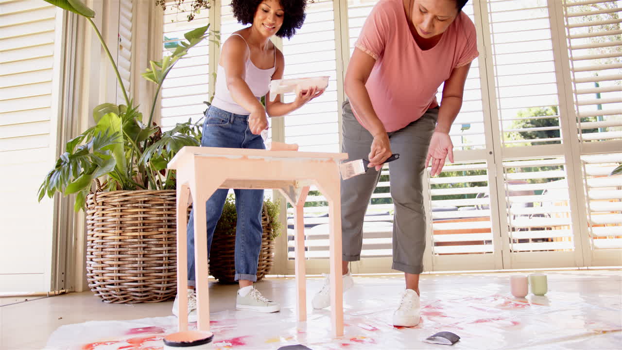 Painting wooden table, mother and adult daughter enjoying DIY home improvement project together