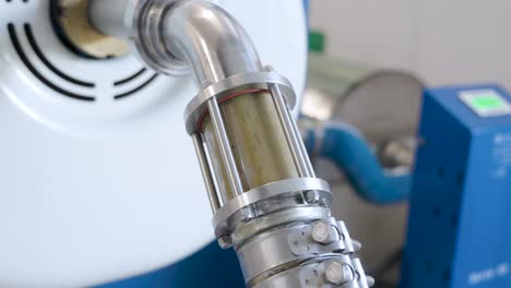 un tubo conectado a una gran máquina que transporta aceitunas trituradas que se están procesando para crear aceite de oliva virgen extra orgánico fresco en una instalación de producción en la región de abruzzo, italia