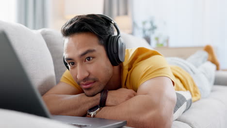 man on couch with laptop, headphones