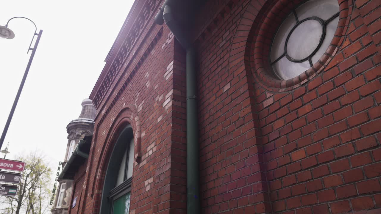 공업 스타일의 시장 홀의  ⁇ 은 벽돌 정면의 클로즈업으로 원형 창문과 1899 년으로 거슬러 올라가는 판이 있습니다.