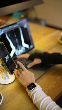 medical professional reviewing x-ray images on laptop and smartphone