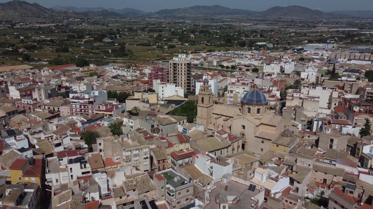 Vista aérea voando em direção à histórica cidade antiga de Aspe e à emblemática Basílica de Nossa Senhora da Ajuda em Alicante, Espanha. Imagens de arquivo de viagem de uma pitoresca vila europeia