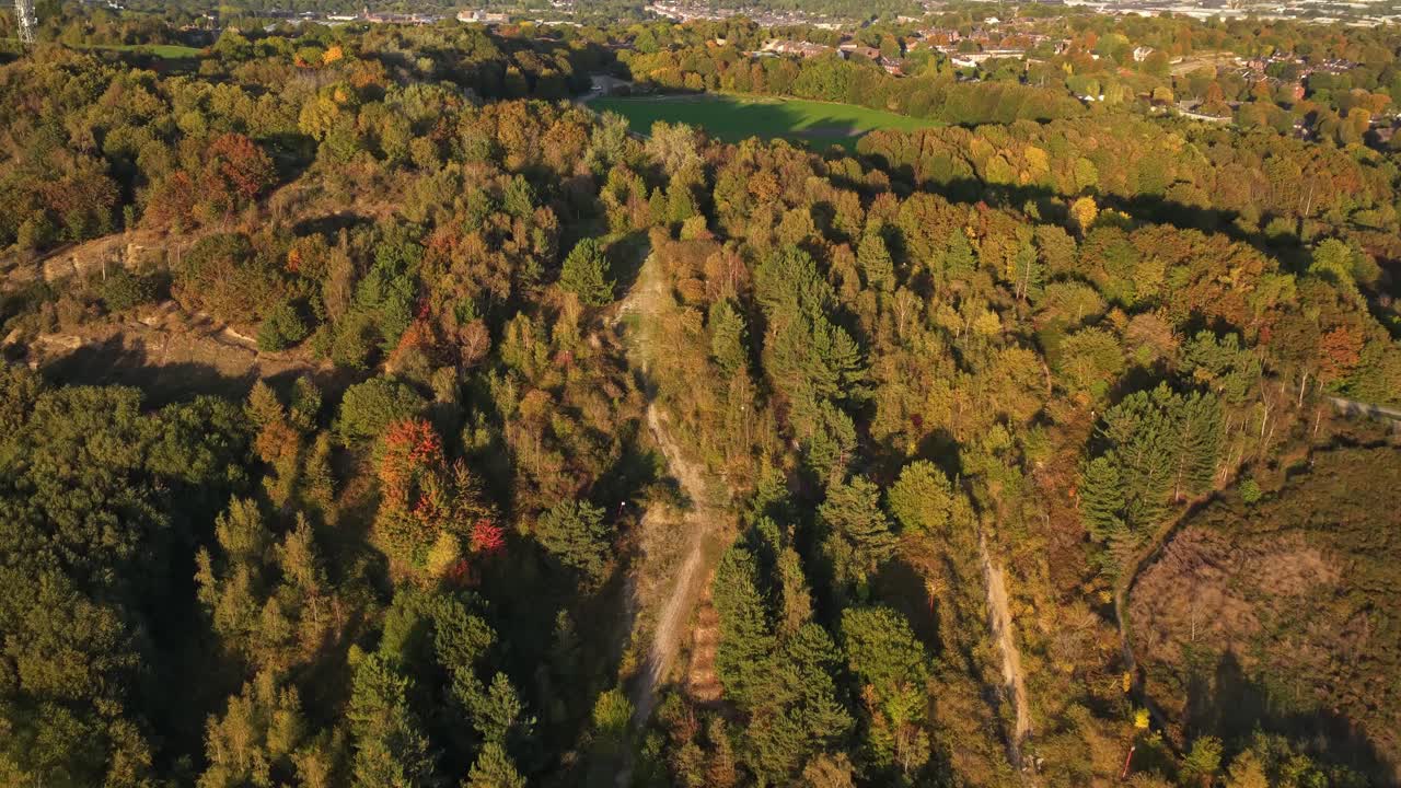 Drone scene over the former Sheffield Ski Village in Parkwood Springs captures a striking autumn tapestry—where winding forest trails, vibrant foliage, and distant urban rooftops
