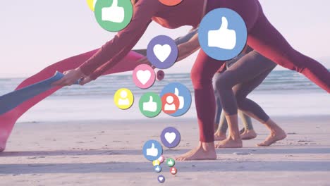 animation of media icons over diverse women with yoga mats at beach