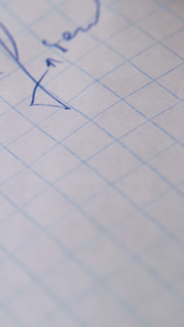 young man writes letter to friend with blue pen on blank checkered paper sheet extreme close view