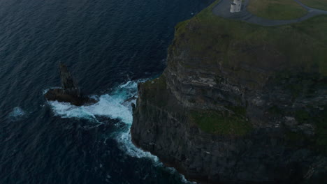 Blick-Aus-Dem-Hohen-Winkel-Auf-Wellen,-Die-An-Der-Felsigen-Küste-Zusammenbrechen.-Hohe-Klippen-Und-Aussichtspunkt-Oben.-Klippen-Von-Moher,-Irland