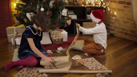 linda niña y su hermano envolviendo regalo de navidad