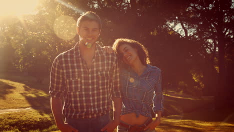 Happy-couple-looking-at-camera-in-park