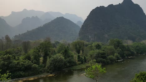 Flying-the-drone-over-the-trees-in-Laos,-capturing-an-amazing-aerial-view-of-the-mountains-ahead