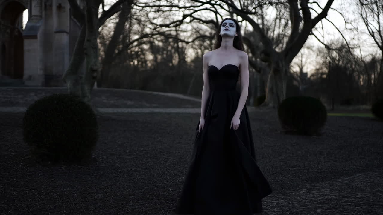 Donna inquietante in abito nero in posa in un oscuro parco gotico