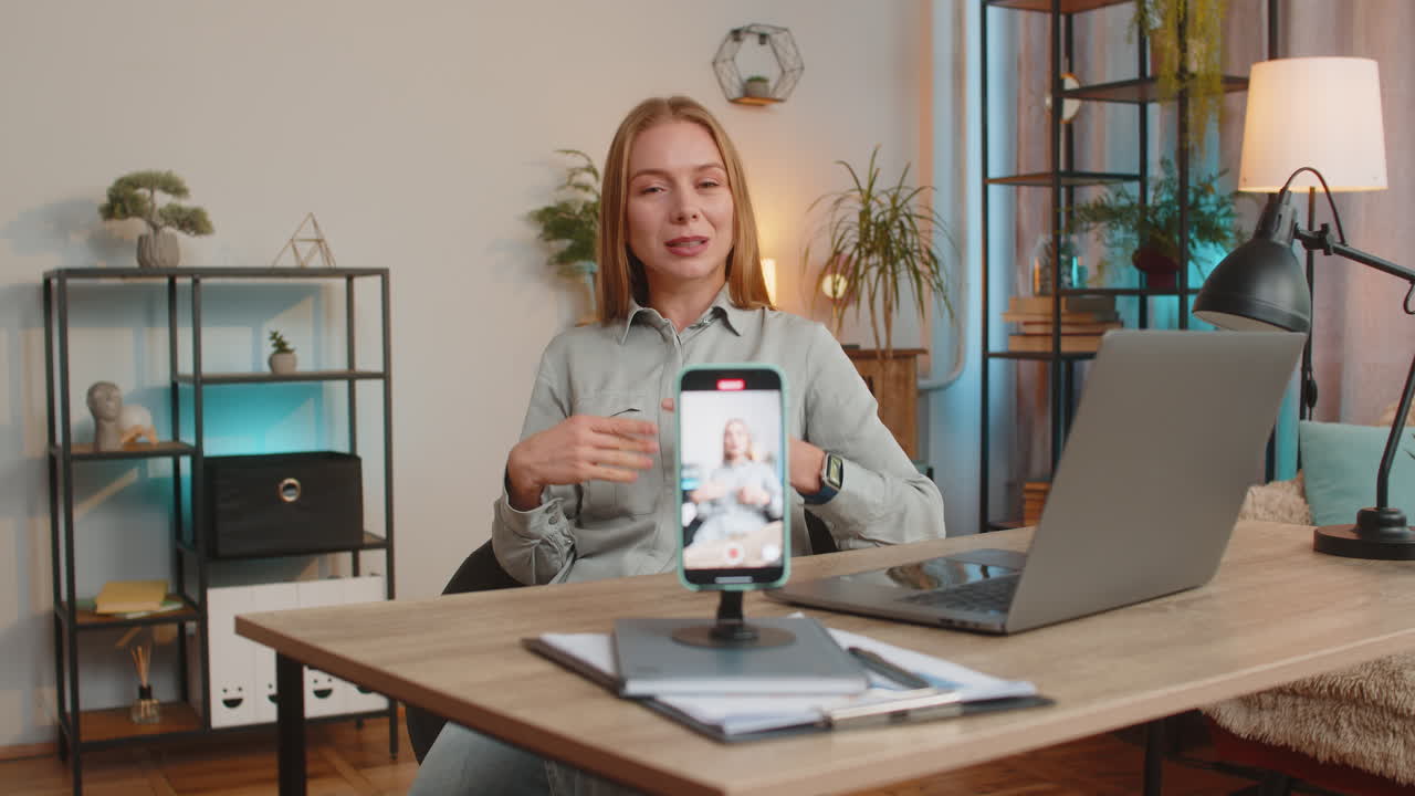 mujer de negocios sonriente registro de motivación capacitación webinar en cámara web a través de teléfono inteligente en la oficina de casa