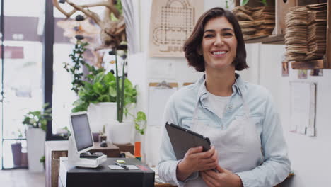 retrato de la propietaria femenina con una tableta digital de pie detrás de la mesa de ventas de la tienda de floristas