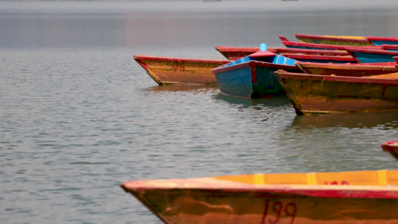 Colorful wooden boats in a lake. Traditional boats parked at the shore of Begnas Lake in  Nepal