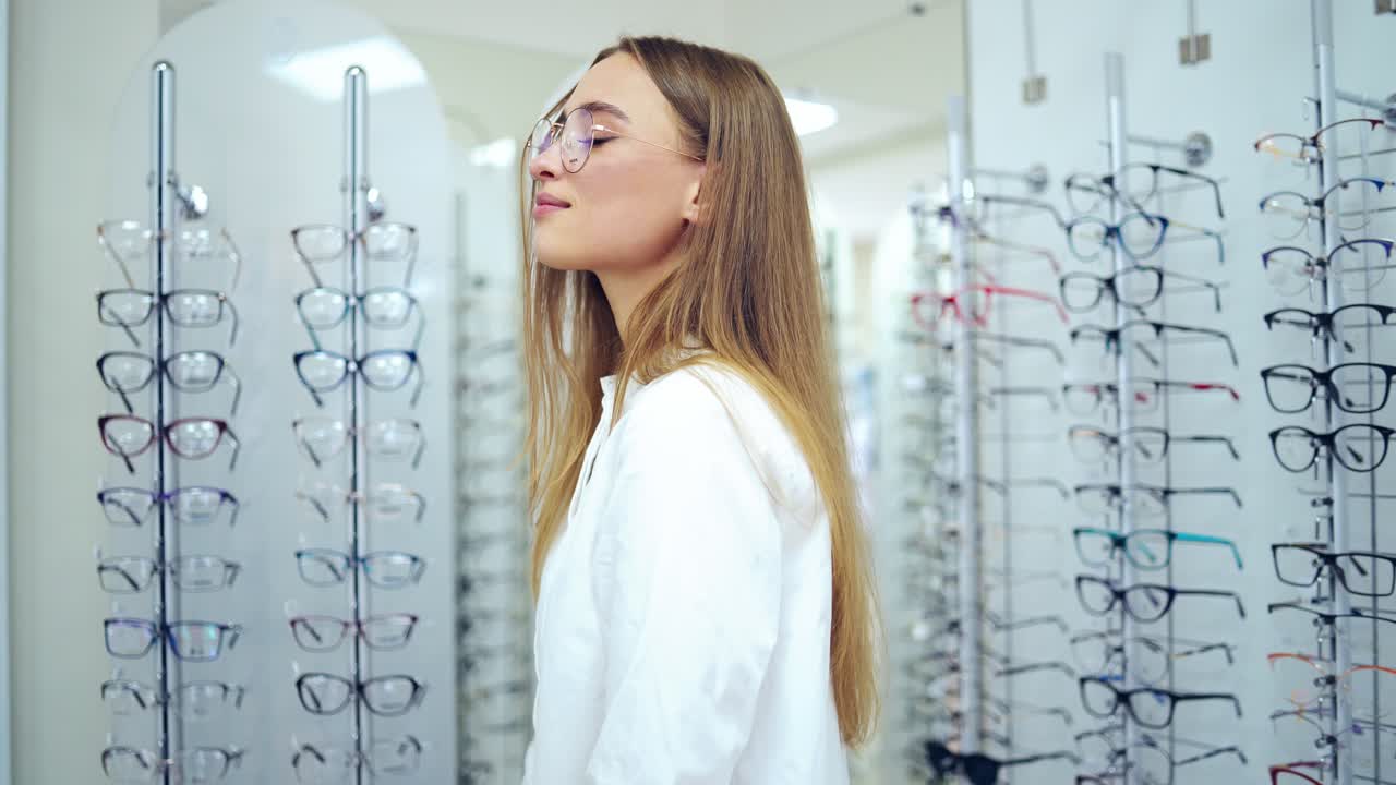 Smiling woman in new eyeglasses. Happy young female buyer choosing stylish spectacles at optical shop. Healthy eyesight.